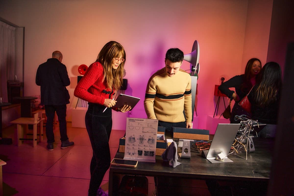 Guests trying Breezm frames at the eyewear table under pink gallery light