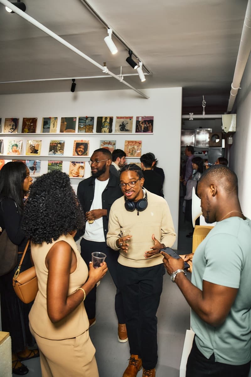 Guests in conversation along the record wall at a Mesh event